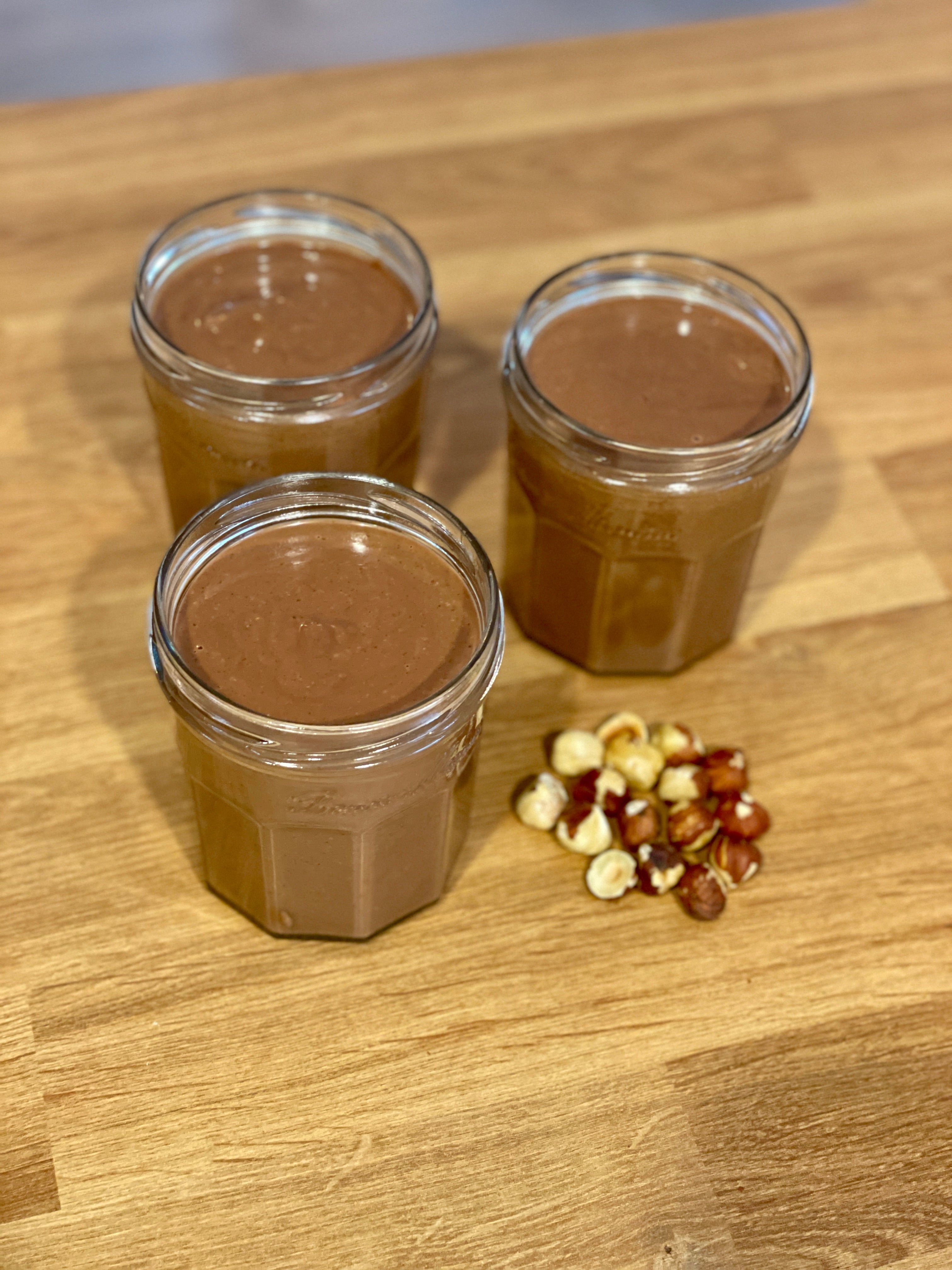 Creamy homemade chocolate hazelnut spread in glass jars, made with roasted hazelnuts and melted milk chocolate, ready to serve on toast or crêpes