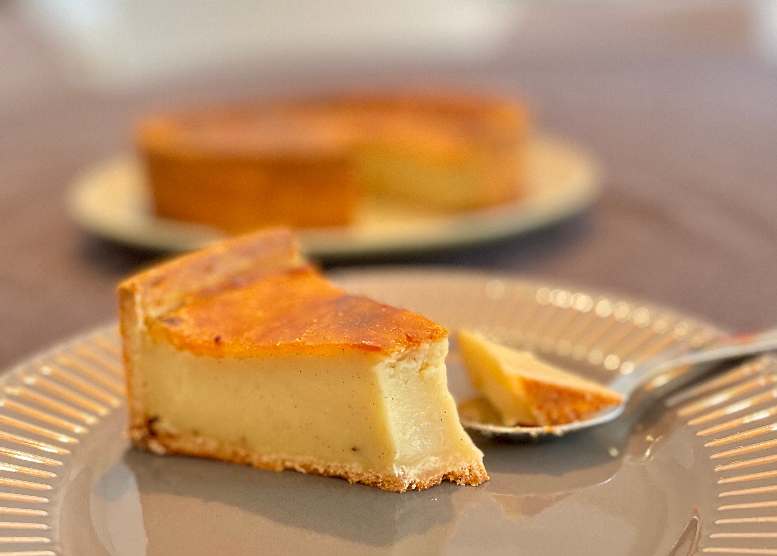 Golden-baked Parisian flan in a shortcrust pastry shell, sliced to reveal smooth vanilla custard filling, served on a rustic wooden board.